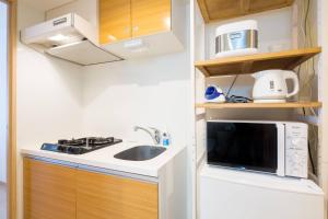 a small kitchen with a sink and a microwave at ID Ohmori20 in Tokyo