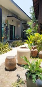 a garden with large pots and plants in front of a house at Marin' s Home in Thalang