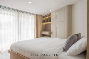 a bedroom with a white bed and a large window at The Palette Dalat in Da Lat