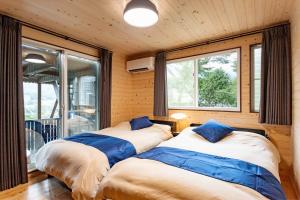 two beds in a room with a window at Villa Noël HAKONE FUJI Sauna&Open Air Bath in Hakone