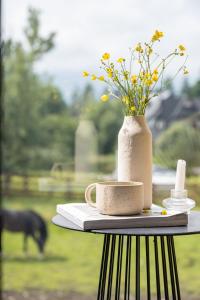 una mesa con un jarrón con flores. en Rychlinowe Domki en Poronin