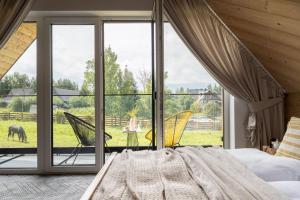 a bedroom with a bed and views of a field at Rychlinowe Domki in Poronin