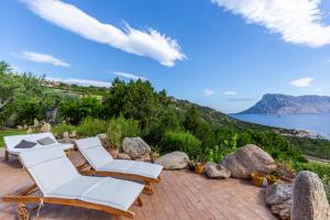 a patio with white chairs and a view of the ocean at Villa Rubia - Belocations in Monte Petrosu