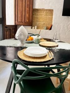 a black table with a plate and a green chair at Ruggine Loft in Gallipoli