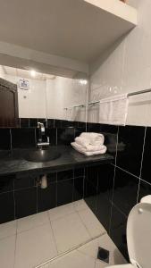 Appartement au coeur d'Aourir في أورير: حمام أسود وبيض مع حوض ومرحاض