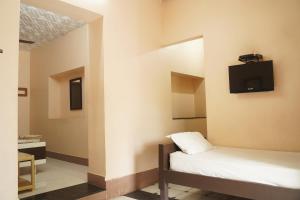 a room with two beds and a tv on the wall at SOWMYA LODGE in Tiruchirappalli