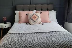 een bed met roze en witte kussens erop bij St Davids Central Apartment in Exeter