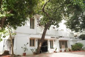 a white building with a tree in front of it at SOWMYA LODGE in Tiruchirappalli