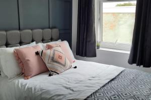 een bed met roze en witte kussens en een raam bij St Davids Central Apartment in Exeter