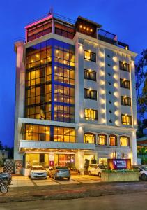 a building with cars parked in front of it at Regenta Place Raysons Kolhapur in Kolhapur