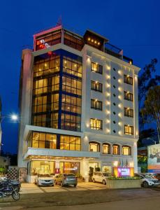 a building with cars parked in front of it at Regenta Place Raysons Kolhapur in Kolhapur