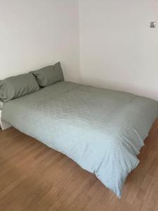 łóżko z zielonym kocem na drewnianej podłodze w obiekcie 3 bedrooms flat Crystal Palace w Londynie