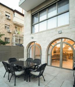 eine Terrasse mit einem Tisch und Stühlen vor einem Gebäude in der Unterkunft Hapalmah One, Jerusalem, Dira 2 in Jerusalem