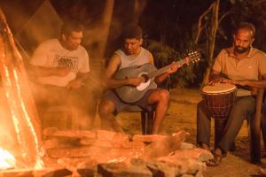 un grupo de hombres tocando la guitarra y la batería junto al fuego en The New Crown Hotel, en Dambulla