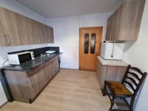 cocina con armarios de madera, microondas y silla en ONE Self-Check-In, 3km freeway, 