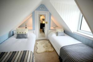 a attic room with two beds and a staircase at Dram Cottage, Findhorn Bay in Forres