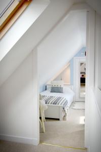 a white bedroom with a bed and a staircase at Dram Cottage, Findhorn Bay in Forres