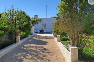 a pathway leading to a house with trees and a table at Punta Grossa - Porto Cesareo in Punta Prosciutto