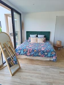 1 dormitorio con cama y espejo en Le Pavillon des pivoines, en Hyères