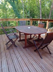 un tavolo in legno e 2 sedie su una terrazza di Gîte le noisetier 3-6 personnes a Blésignac