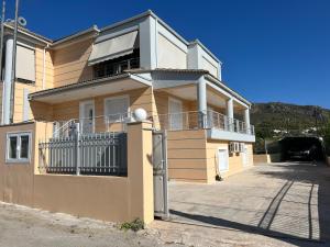 Edificio amarillo con balcón y puerta en Apartment Mitrou en Loutra Oraias Elenis 