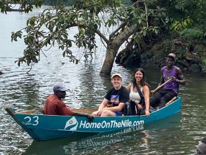um grupo de pessoas sentadas em um barco azul na água em Home On The Nile water front Cottage em Jinja