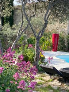 um jardim com um banco e flores e uma árvore em Mas de la Beaume em Gordes