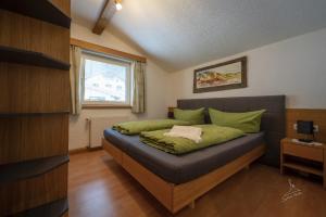 a bedroom with a bed with green sheets and a window at Ferienwohnung Kobler in Landeck