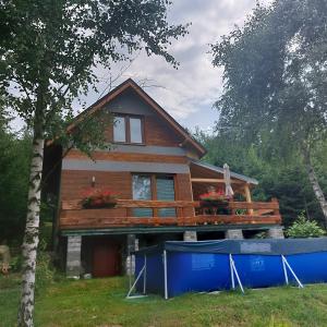 une maison avec une terrasse sur le côté dans l'établissement Świerkowy Zakątek u Bacy, à Wieprz