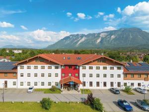 un grand bâtiment blanc avec des voitures garées dans un parking dans l'établissement Hey Lou Hotel Piding, à Piding