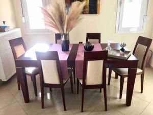 einen Esstisch und Stühle mit einem lila Tisch und einer Vase in der Unterkunft Villa Marina in Perama