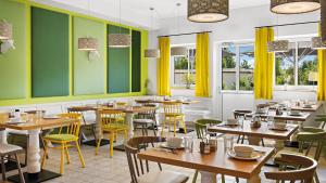 ein Restaurant mit Holztischen und gelben Wänden und Fenstern in der Unterkunft Hey Lou Hotel Piding in Piding