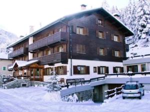 a large building with a car parked in the snow at Residence Valfurva in Santa Caterina Valfurva