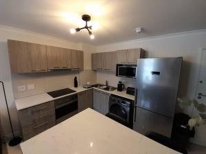 eine Küche mit einem Kühlschrank und Schränken aus Edelstahl in der Unterkunft Modern Apartment in Chapel Towers (with Inverter) in Kapstadt