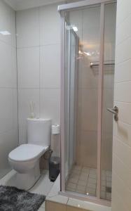 a bathroom with a toilet and a glass shower at Modern Apartment in Chapel Towers (with Inverter) in Cape Town