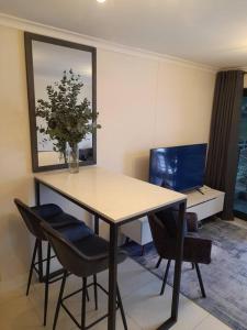 a table with chairs and a vase with a plant on it at Modern Apartment in Chapel Towers (with Inverter) in Cape Town