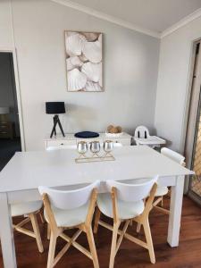 a white dining room with a white table and chairs at House on Ryan in Broken Hill