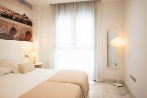een slaapkamer met een wit bed en een groot raam bij Monteras Córdoba Centro in Córdoba