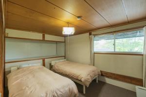 two beds in a small room with a window at 交流宿　星降る家　いこい in Gujo
