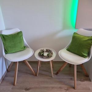 two white chairs with green pillows sitting next to a table at Mountain view apartments in Bad Mitterndorf