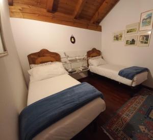 2 bedden in een kleine kamer met houten plafonds bij B&B il Ciliegio di Maura in Massimeno