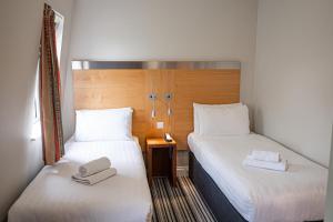 two beds in a hotel room with towels on them at Maiden Oval in London