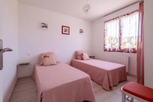 - 2 lits dans une chambre blanche avec des draps roses dans l'établissement Logis de la Perruche - Maison avec terrasses, à Montreuil-Bellay