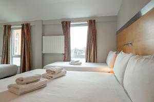 a hotel room with two beds with towels on them at Maiden Oval in London