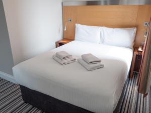 a large white bed with two towels on it at Maiden Oval in London