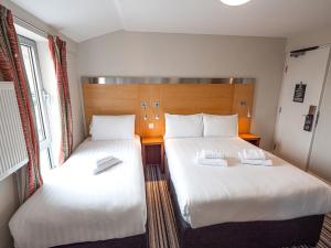 duas camas num quarto de hotel com lençóis brancos em Maiden Oval em Londres