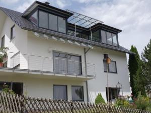 ein großes weißes Haus mit Balkon darüber in der Unterkunft Haus Am Waldpark in Sankt Georgen im Schwarzwald