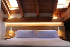 a bedroom with a bed with two pillows and two windows at Hotel Saurat in Espot