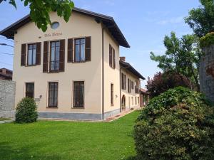 a white house with brown windows and a yard at VILLA BOTTERA with Jacuzzi in the garden Cuneo Langhe Piemonte in Riforano
