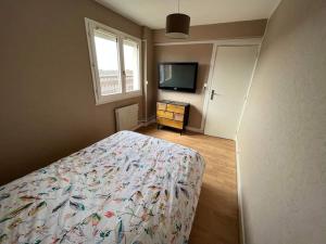 a bedroom with a bed and a flat screen tv at Superbe appartement proche de la plage in Dunkerque